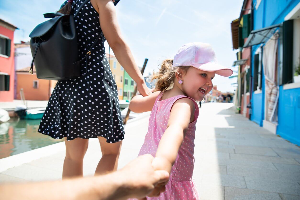 fille de sourire avec leurs parents marchant sur la rue de burano