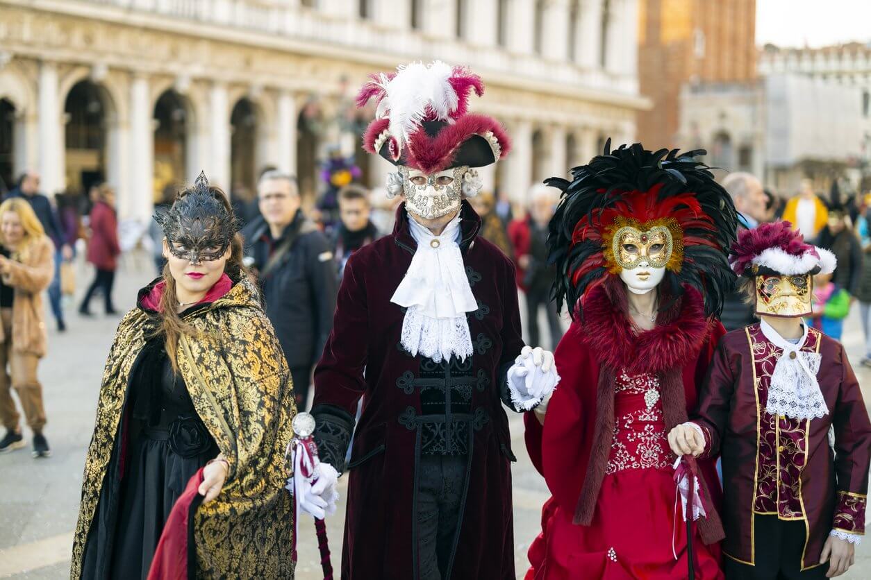 une famille en costumes de masques venitiens classiques sur la place san marco