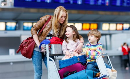 Little girl and boy and young mother with suitcases