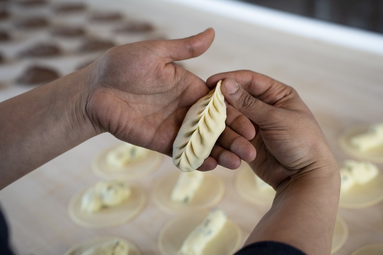 Close up of female hands showing fresh homemade culurgiones pasta. Italian typical filled pasta from Sardinia region