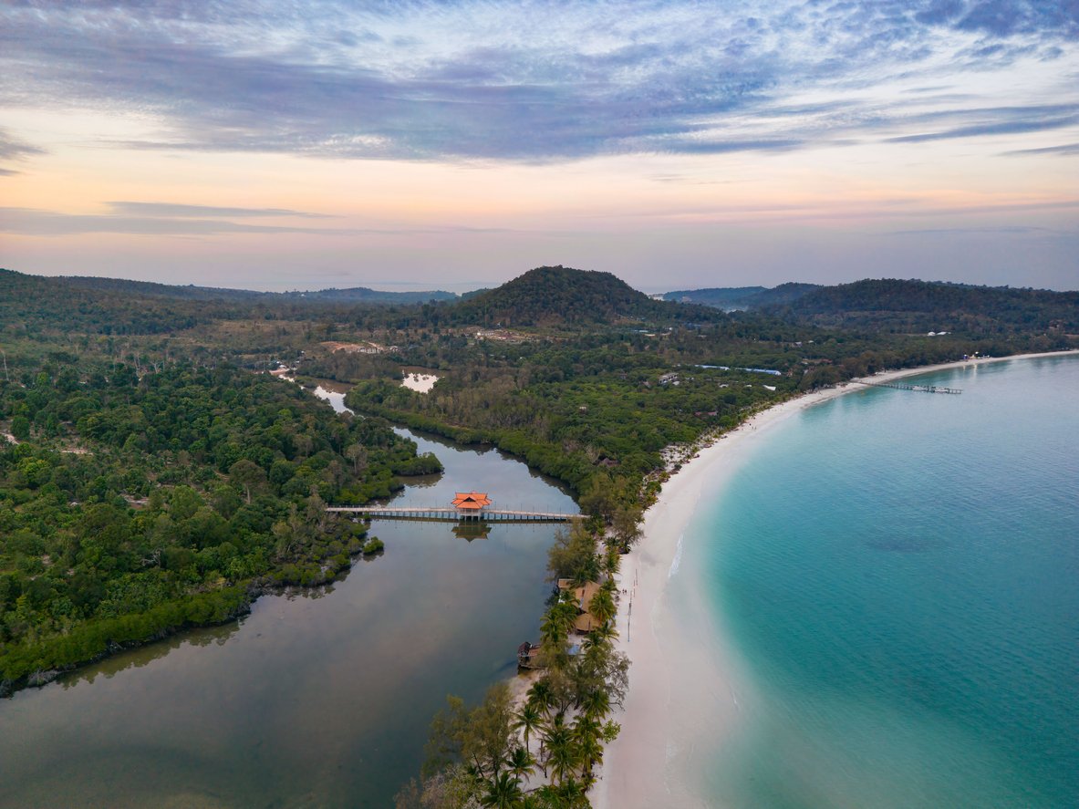 Aerial view of Koh Rong beach surrounded by dense trees during sunset