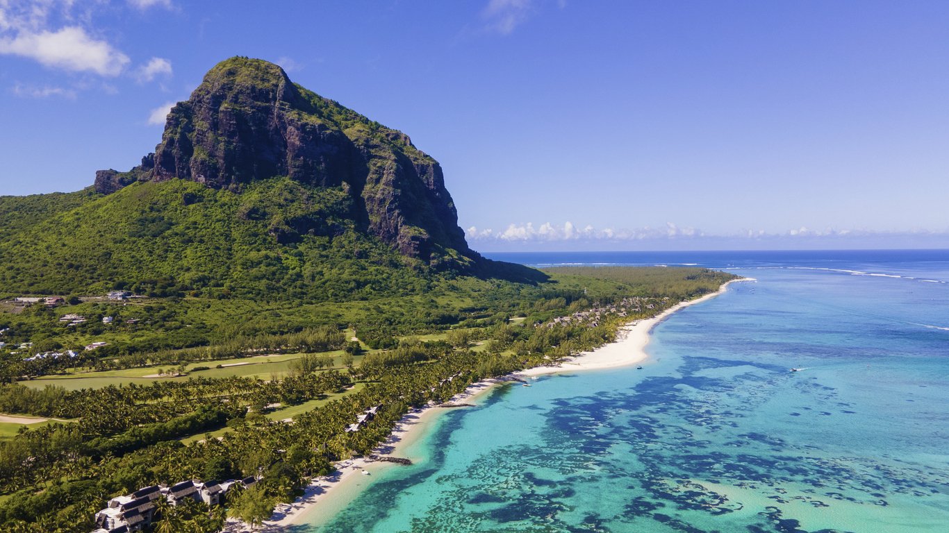 Le Morne beach Mauritius,Tropical beach with palm trees and white sand blue ocean and beach beds with umbrella,Sun chairs and parasol under a palm tree at a tropical beac, Le Morne beach Mauritius