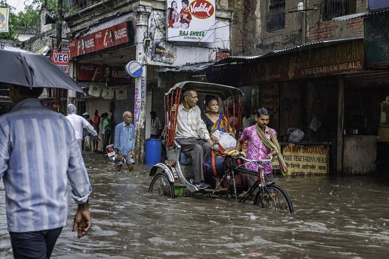 Pousse-pousse et les passagers de négocier une inondation, Varanasi, Inde.