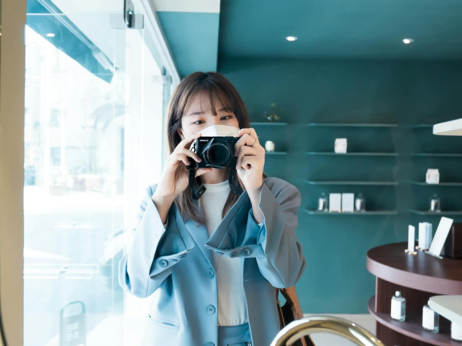 woman in blue blazer holding a black camera