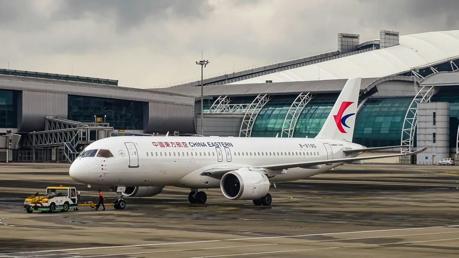 China Eastern Airlines Airbus A320 on the runway at a modern international airport terminal.